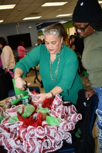 RCC Holiday Craft Fair Vonda Graham assits a student with the bow on her wreath.