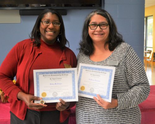 Two women holding 30 year certificates