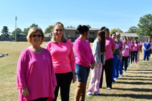Nursing students stand to make a human pink ribbon in middle of campus