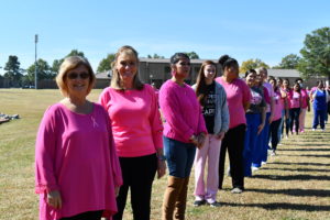 Nursing students stand to make a human pink ribbon in middle of campus