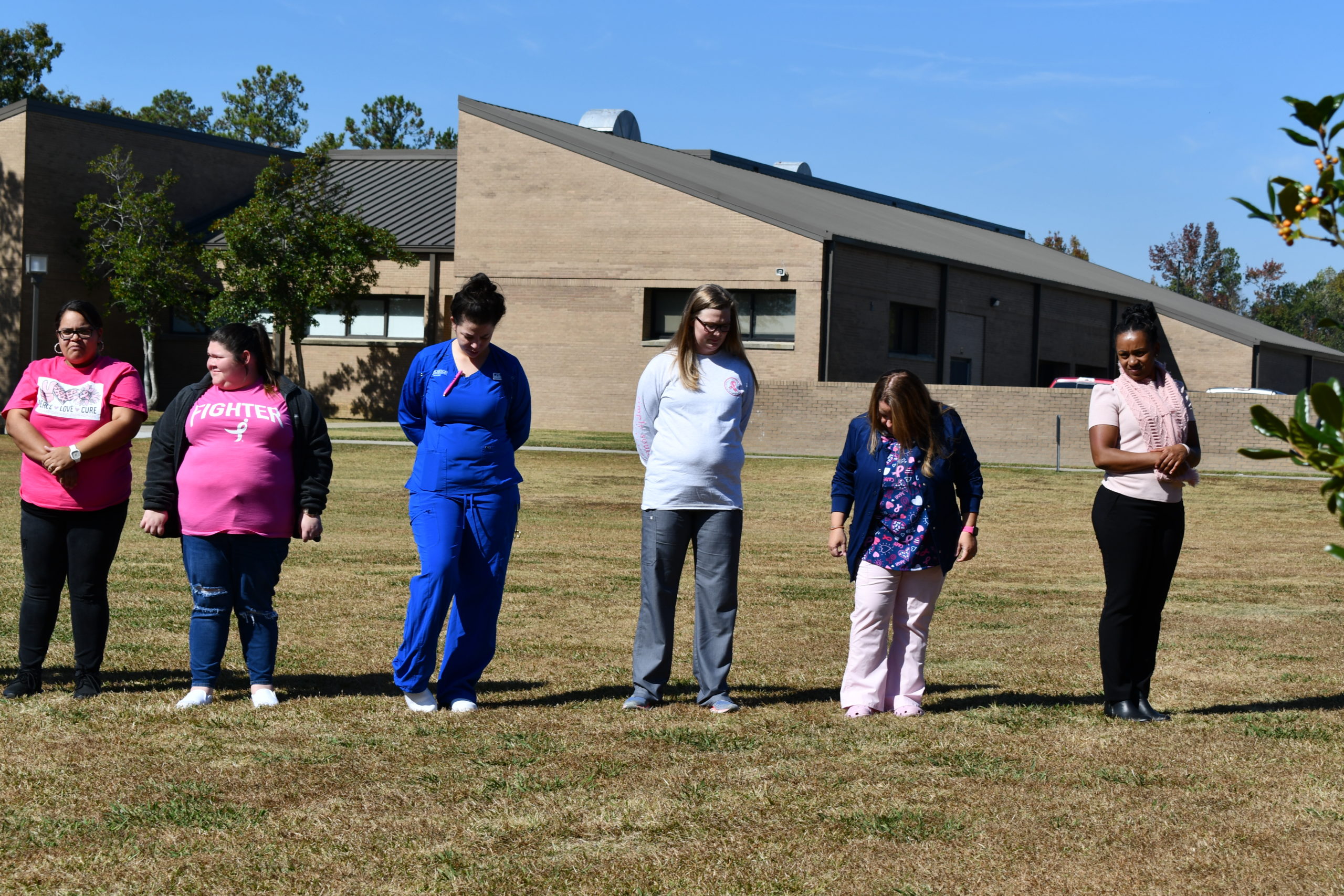 Nursing students stand to make a human pink ribbon in middle of campus