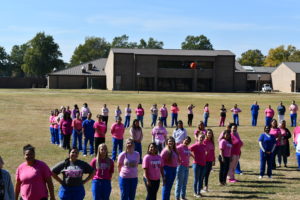 Nursing students stand to make a human pink ribbon in middle of campus