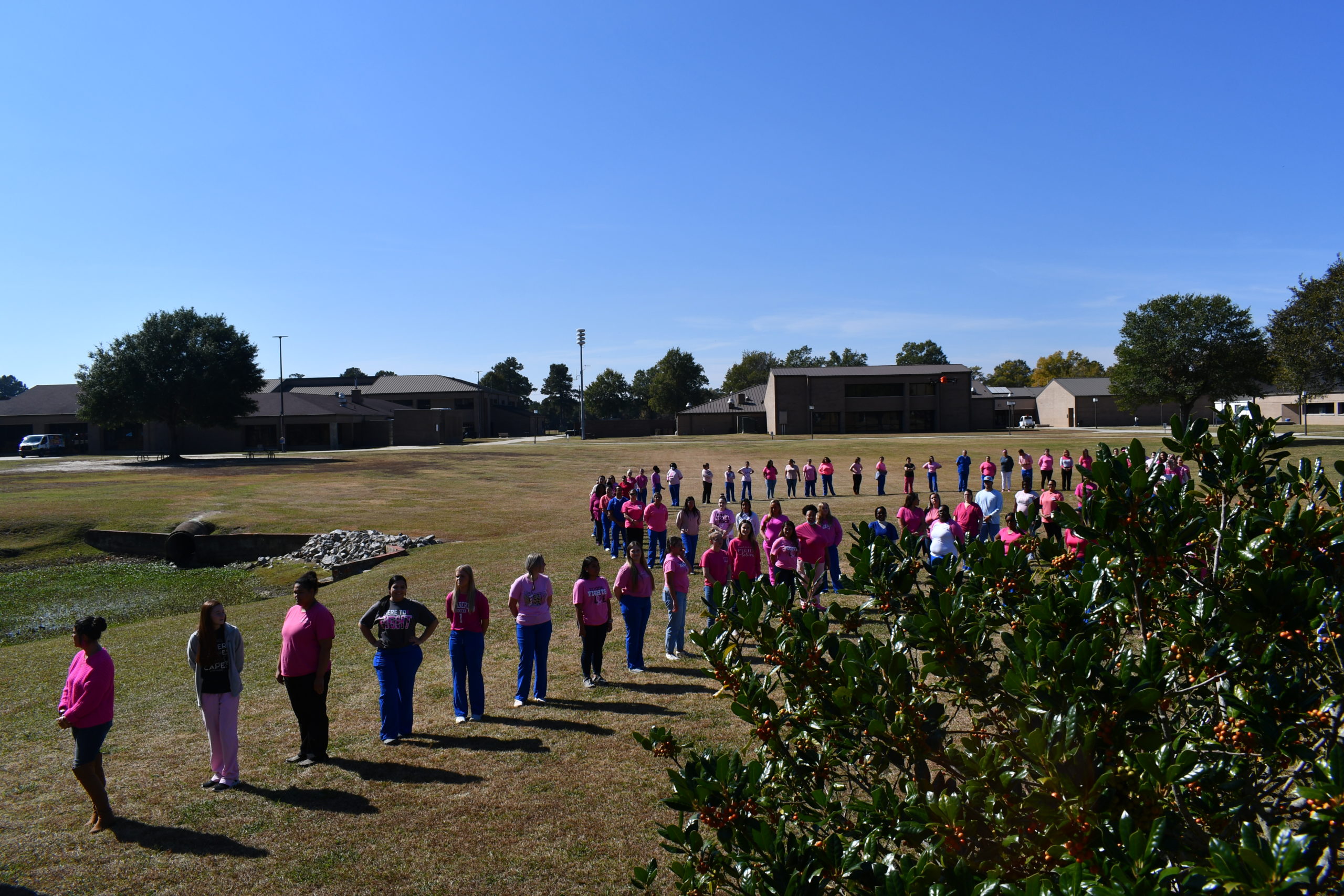 Nursing students stand to make a human pink ribbon in middle of campus