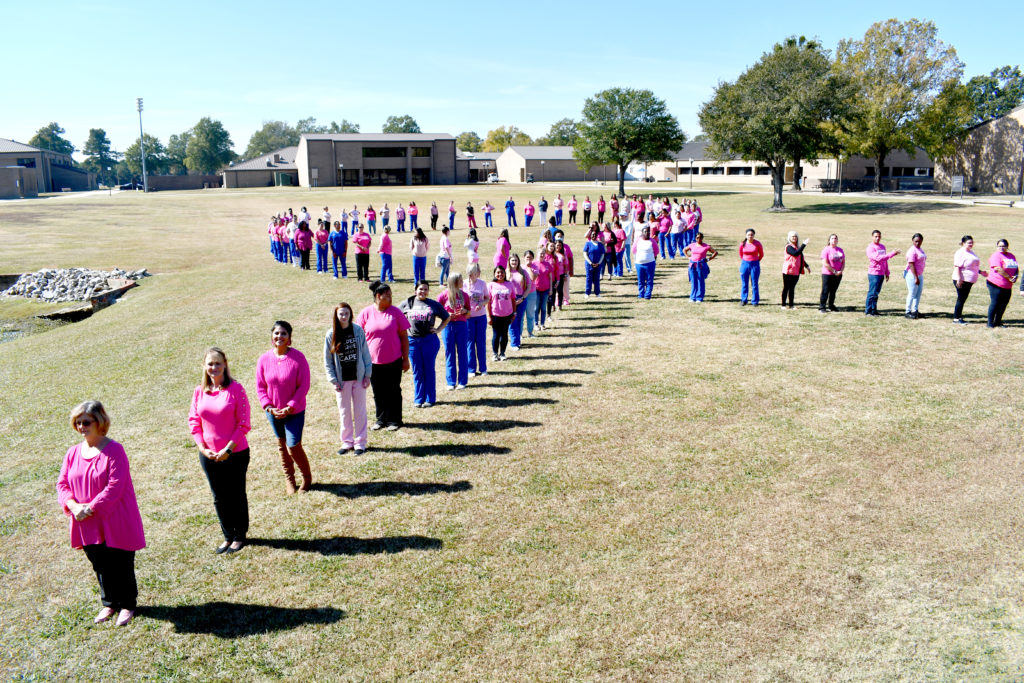Nursing students stand to make a human pink ribbon in middle of campus