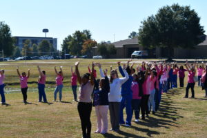 Nursing students stand to make a human pink ribbon in middle of campus