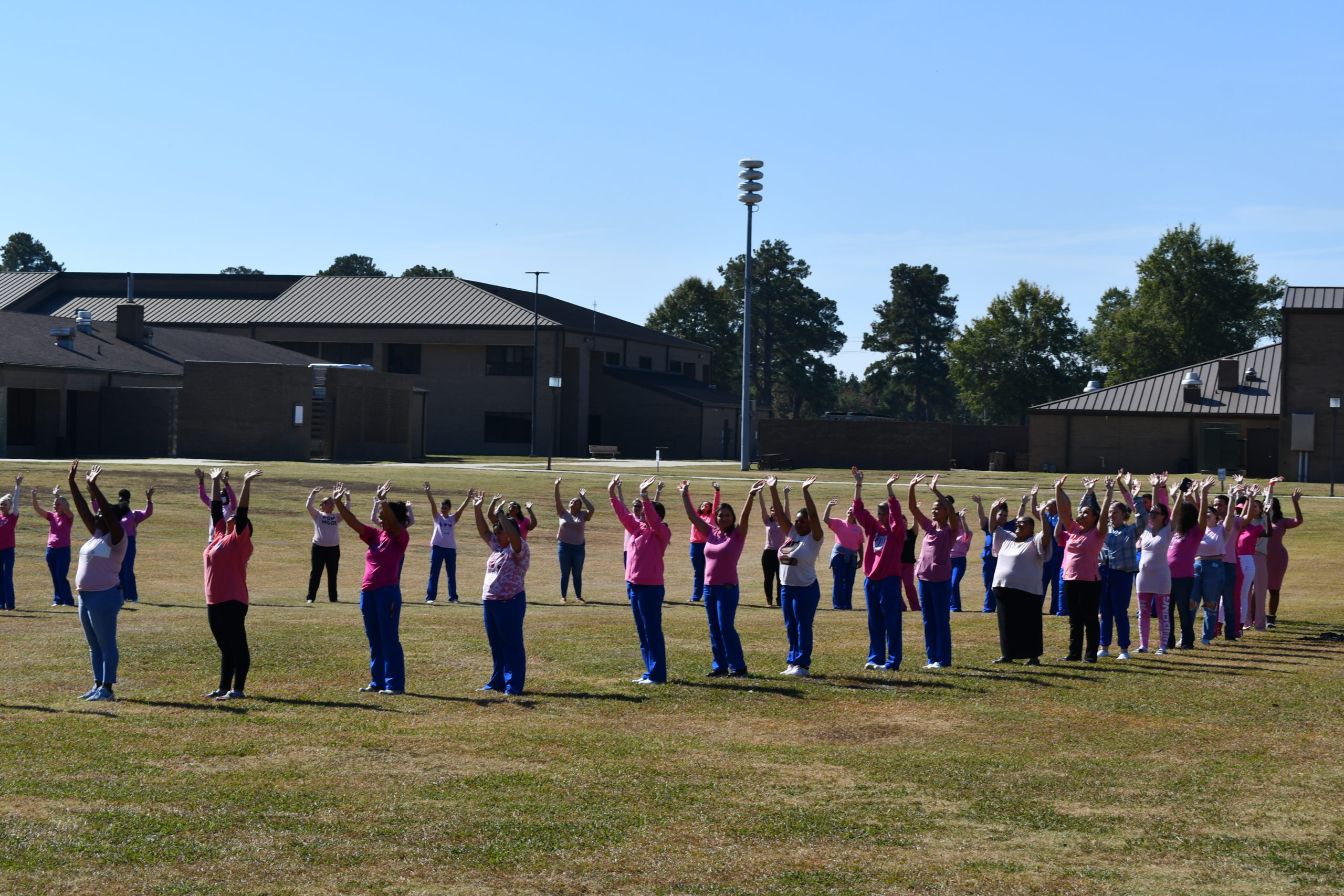 Nursing students stand to make a human pink ribbon in middle of campus