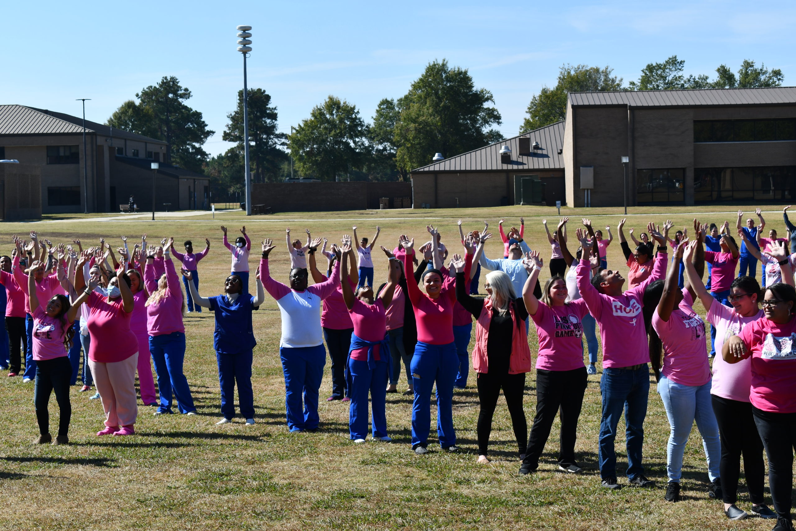 Nursing students stand to make a human pink ribbon in middle of campus