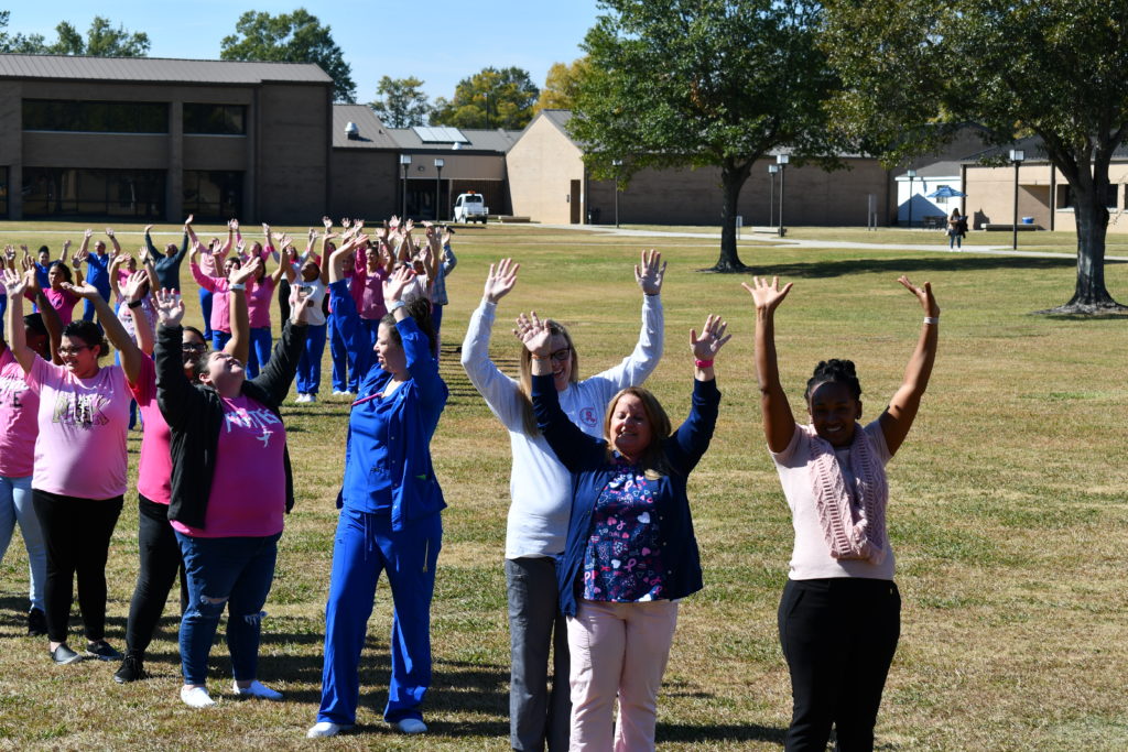 Nursing students stand to make a human pink ribbon in middle of campus