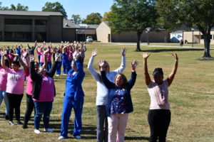 Nursing students stand to make a human pink ribbon in middle of campus