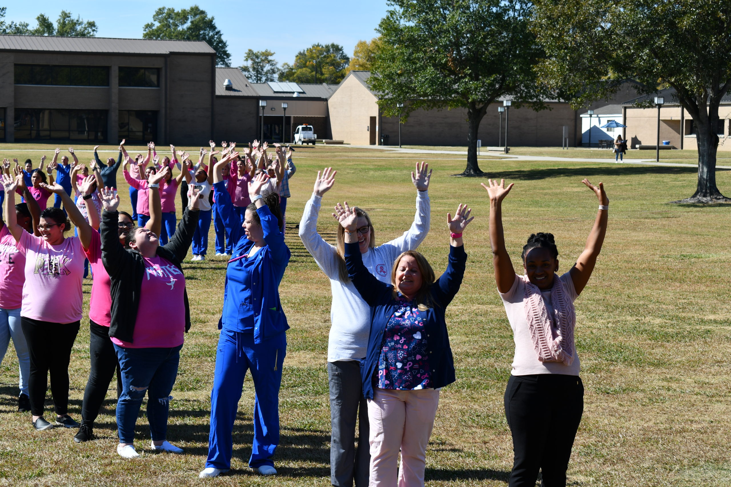 Nursing students stand to make a human pink ribbon in middle of campus