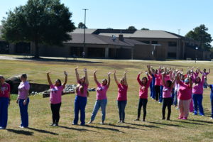 Nursing students stand to make a human pink ribbon in middle of campus