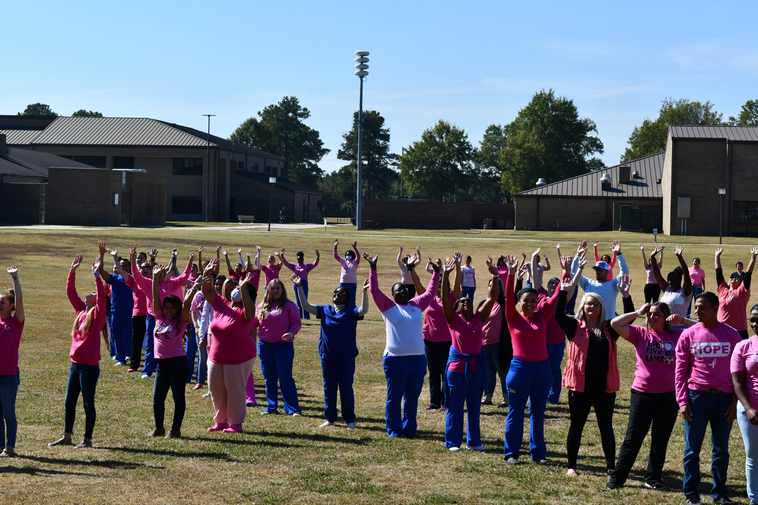 Nursing students stand to make a human pink ribbon in middle of campus