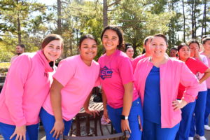 Nursing students stand to make a human pink ribbon in middle of campus