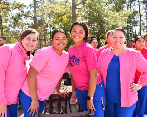 Nursing students stand to make a human pink ribbon in middle of campus