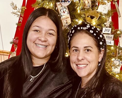 Mother and daughter seated in front of Christmas tree