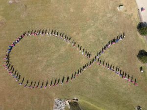 Nursing students stand to make a human pink ribbon in middle of campus