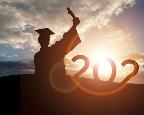 2022 Graduate Standing facing sunset with diploma in hand