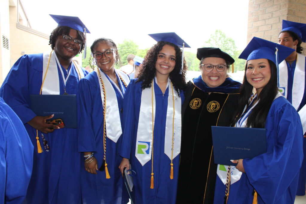 A photo featuring 4 students and a faculty member at a gradation ceremony.