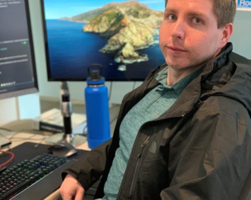 Man looking at camera with computers surrounding him